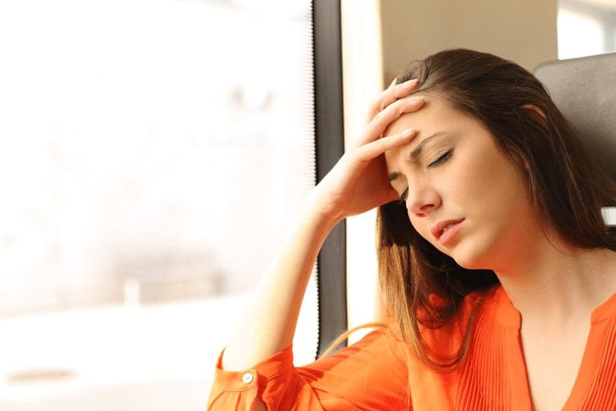 Picture of woman with headache on train leaning against window