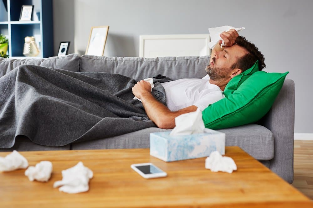 Picture of Sick man with fever lying on couch at home