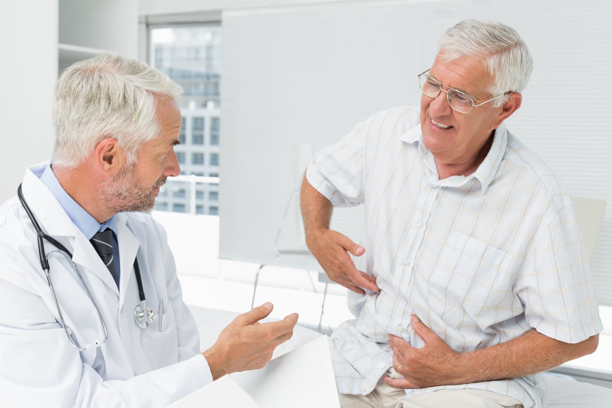 patient explaining where his stomach pain is to a doctor
