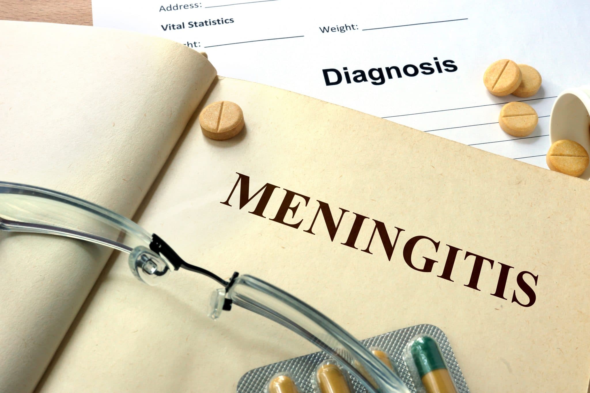Picture of Word Meningitis on a book and pills.