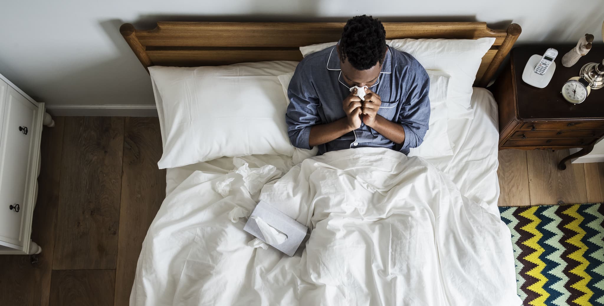 Sick man on bed blowing his nose