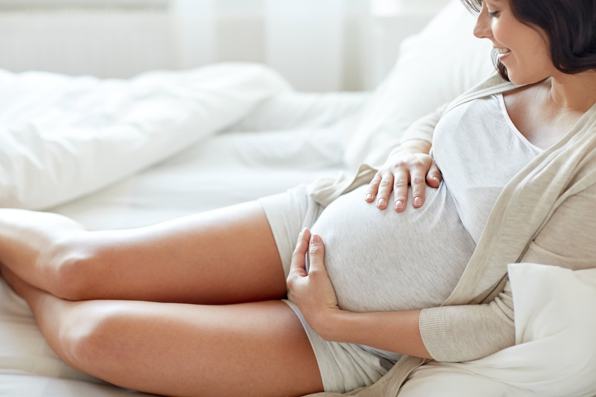 Picture of close up of happy pregnant woman in bed at home